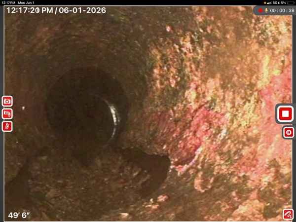 Sewer pipe camera inspection footage showing interior pipe condition with visible deterioration and buildup at approximately 49 feet 6 inches depth.