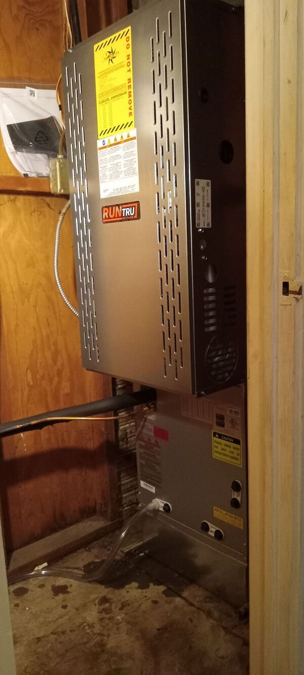 A RunTru by Trane HVAC air handler unit installed in a utility closet, showing the unit, refrigerant lines, and surrounding framing.